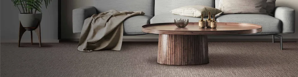 Neutral textured carpet beneath a sofa and round coffee table